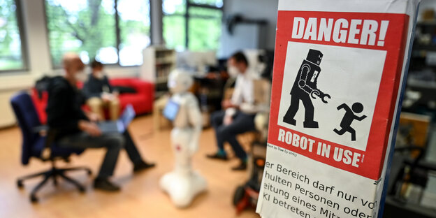 Warnschild vor Roboter in Anwendung, Roboter im Hintergrund
