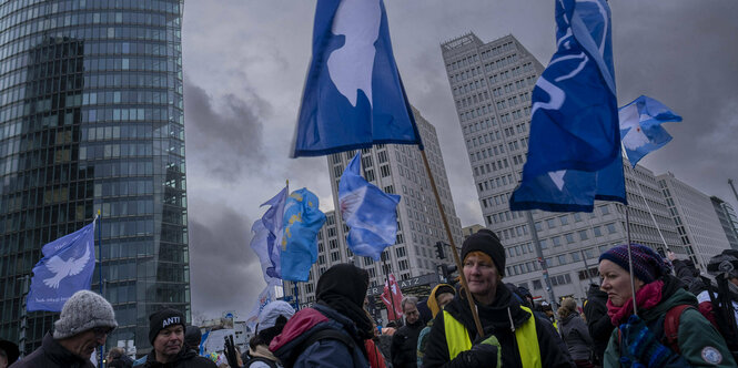 Demonstranten mit Fahnen, auf denen Friedenstauben abgebildet sind