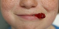 Ein Gummibärchen im Mund eines Kindes