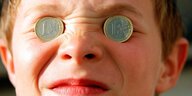 Kind mit Münzen auf den Augen