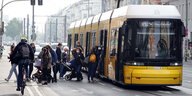 Menschen steigen in eine gelbe Straßenbahn