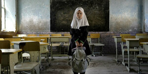 Ein Mädchen mit Schulranzen in einem leeren Klassenraum