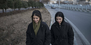 zwei iranische Frauen gehen mit bedeckten Haaren auf einer Straße