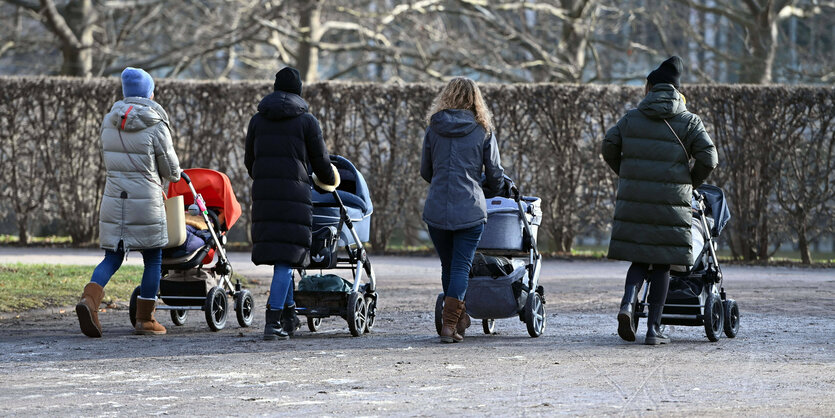 4 Frauen in Wintermänteln schieben 4 Kinderwagen