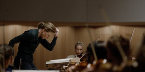 Lydia Tár (Cate Blanchett) dirigiert eine Probe, im Hintergrund sitzt die Konzertmeisterin Sharon (Nina Hoss)