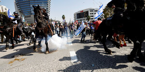 Rauchbomben auf einer Straße mit Demonstranten und Polizisten auf Pferden