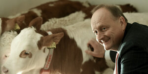 Joachim Rukwied, Bauernpräsident, steht neben einer Kuh.