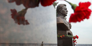 Rote Nelken schmücken eine Bronzebüste mit dem Konterfei Stalins