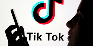 Schattenriß einer Person, die ein Smartphone in der Hand hält, im Hintergrund das TikTok Logo