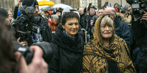 Sahra Wagenknecht und Alice Schwarzer umringt von Presse vor dem Brandenburger Tor