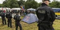 Polizisten stehen vor einem Zelt