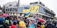 Teilnehmer einer Demo unter dem Motto „Wir werden nie vergessen“ stehen an der Karl-Marx-Allee vor dem Cafe Moskau, das für ein paar Tage in Cafe Kyiv (Kiew) umbenannt wurde, ein Bild vom 24.2.2023