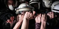 Zur Faust gereckte Hände vor fünf Polizisten mit Helmen