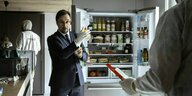 Professor Börne zieht vor einem geöffneten Kühlschrank Gummihandschuhe an