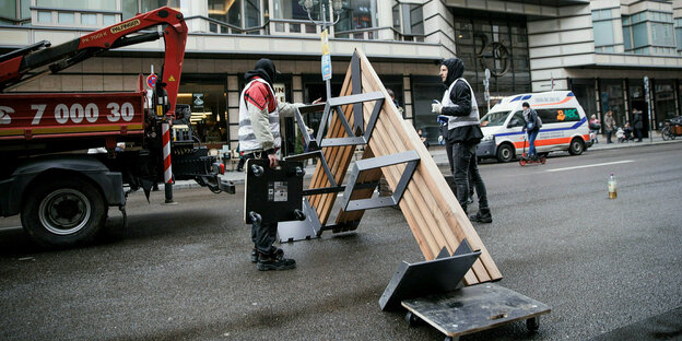 Ein Arbeiter transportiert Sitzbänke auf der Friedrichstraße ab