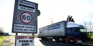 Ein Lastwagen braust an einem Schild vorbei auf dem steht: Welcome to Northern Ireland, das Wort Northern ist durchgestrichen