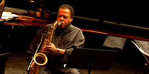 Ein Mann spielt vo rinem Flügel leidenschaftlich Saxophon