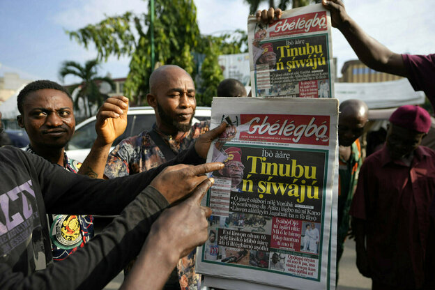 Männer zeigen auf den Titel einer Tageszeitung, die den Sieg Bola Tinubu als Präsident verkündet