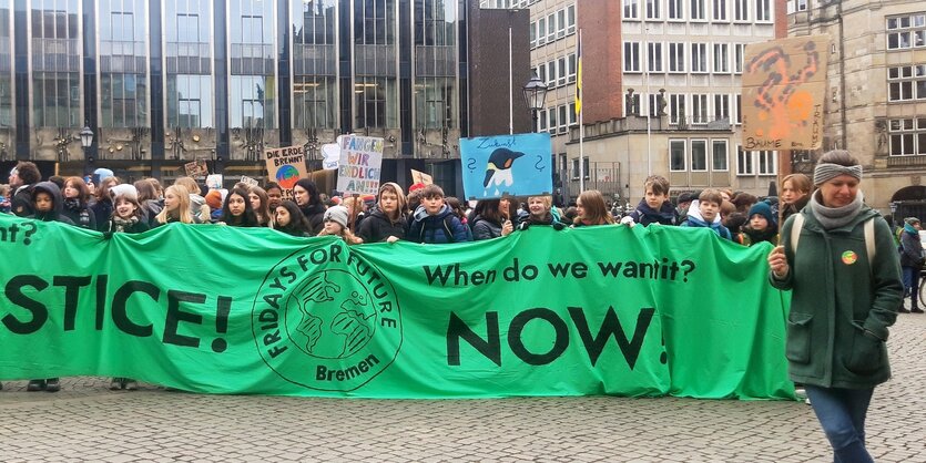 Schülerinnen und Schüler stehen mit einem großen Transparent auf einem Platz