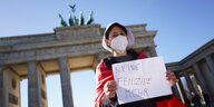 eine Frau steht mit einem Plakat vor dem Brandenburger Tor