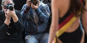 Fotografen fotografieren eine Frau mit einer Deutschlandfahnen-Scherpe