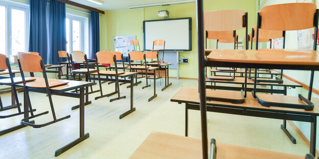 In einem leeren Unterrichtsraum an einer Schule sind die Stühle auf einen Tisch gestellt