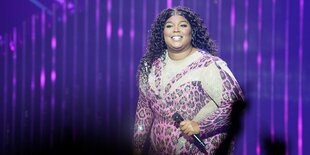 Die Sängerin Lizzo steht mit Mikro auf einer Bühne in der Barclays Arena