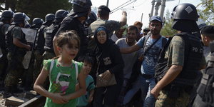 Polizisten kontrollieren Flüchtlinge an der Grenze zwischen Griechenland und Mazedonien.