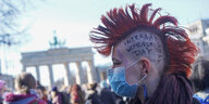 "International Womens Day" steht auf dem Kopf einer Frau, die am Internationalen Frauentag an einer Demonstration vor dem Brandenburger Tor teilnimmt. Seit genau 100 Jahren wird an jedem 8. März weltweit für Frauenrechte, für Gleichberechtigung und Emanzipation demonstriert.