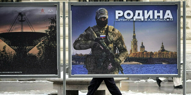 Ein Mann geht an einem Plakat mit dem Bild eines russischen Soldaten und der Aufschrift «Wir verteidigen das Vaterland» vorbei,