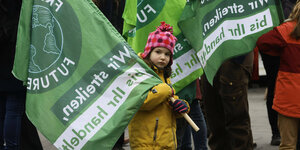 ein Mädchen steht zwischen den grünen Fahnen von "Fridays for Future"