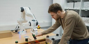 Ein Mann fasst einen Roboterarm an