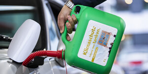 Ein Mann füllt Kraftstoff aus einem Kanister mit der Aufschrift "Klimaschutz könnte man Tanken. E-Fuels for Future" in einen Tank.