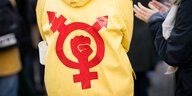 Ein gelber Regenmantel darauf in rot ein Zeichen gegen Antifeminismus