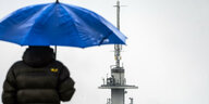 Mann mit Regenschirm vor Mobilfunkmast