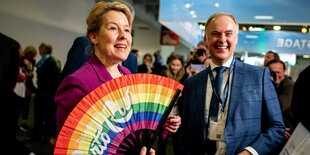 Franziska Giffey hält einen Regenbogenfächer in der Hand, hinter ihr steht ein Mann im Anzug