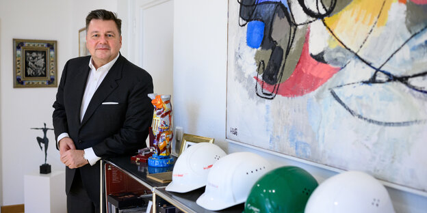 Andreas Geisel (SPD), noch Berliner Bau-Senator, steht in seinem Büro und blickt auf Bauhelme