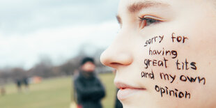 "sorry for having great tits and my own opinion" steht auf der Wange einer Frau, die anlässlich des Internationalen Frauentages bei der Protestaktion "Frauen für Jin, Jiyan, Azadi" für eine "Welt ohne Gewalt" teilnimmt.