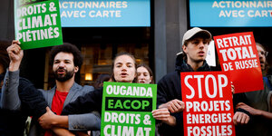 Umweltaktivist:innen demonstrieren mit Schildern wie „Stop Projets Énergies fossiles“