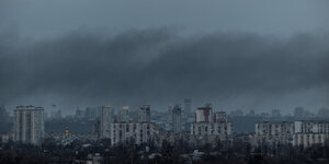 Im Morgengrauen sieht man Rauch über der Skyline von Kyjiw