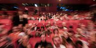 Vollbesetzter Kinosaal mit roten Sesseln und unscharf fotografiert