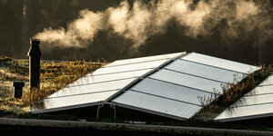 Dach mit Solarpanelen und rauchendem Schornstein