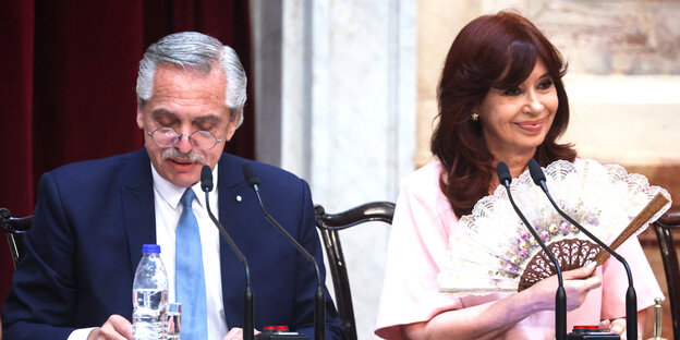 Cristina Kirchner fächert sich zu und der Präsident Alberto Fernandes schaut auf sein Wasser, das auf dem Tisch steht