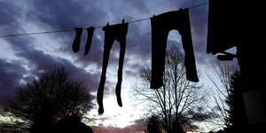 Socken, lange Unterhosen und eine Hose hängt in der Abenddämmerung an einer Wäscheleine