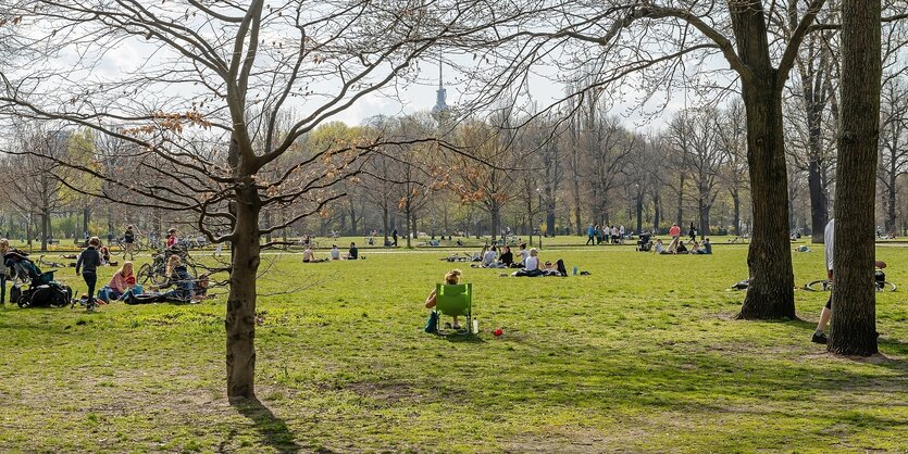 Noch sehr spärlich belaubte Bäume, Wiese, Menschen, zartes Sonnenlicht