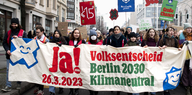 Menschen stehen hinter einem Transparent, das für den Volksentscheid Klima wirbt