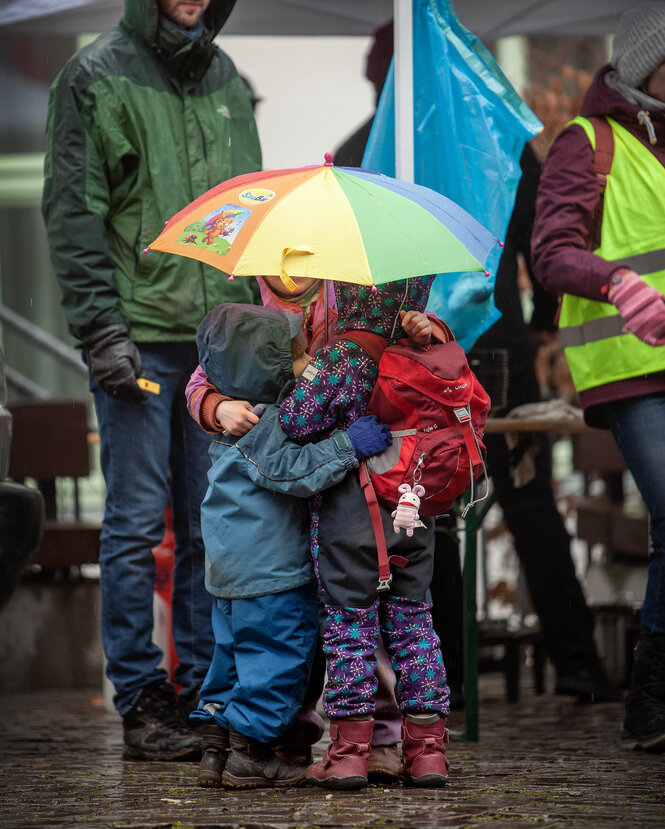 Eine Gruppe Kleinkinder unter einem bunten Regenschirm