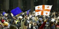 Demonstrierende schwenken die georgische und die EU-Flagge