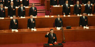 Xi Jinping hebt die Faust während er den Eid spricht, hinter ihm stehen die mundtoten Delegierten