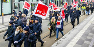 Menschen in blauer Dienstkleidung protestieren gemeinsam mit Verdi-Flaggen in der Hand